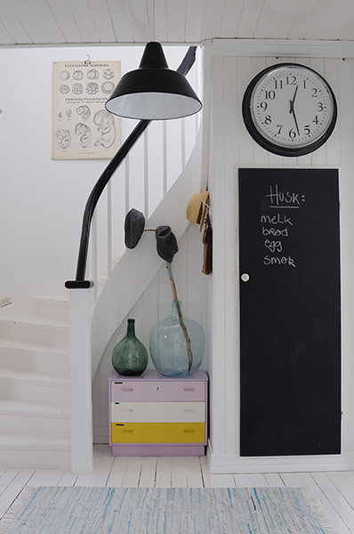 white hallway with stairs with black shade and clock